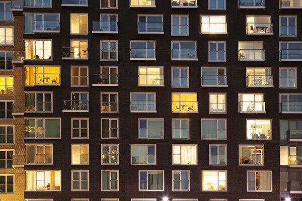 facade of apartment building at dusk with windows lit up