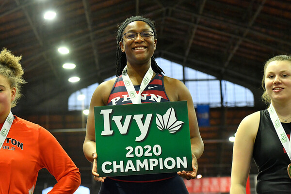 Mayyi Mahama holds a first place board while standing on the first place podium at the Ivy Heps.