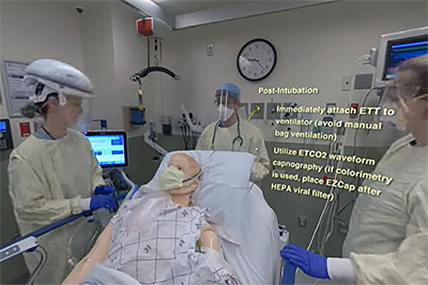 Film still of an intubation training video of a medical dummy and medical students in a hospital room