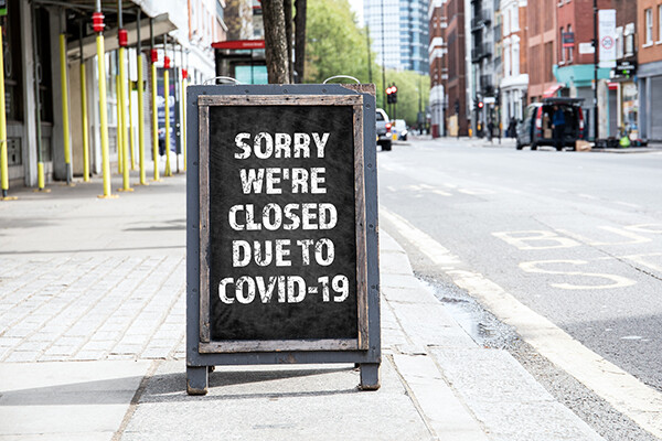 Sandwich board on a city sidewalk that reads “Sorry we’re closed due to COVID-19”