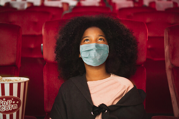Young woman wearing mask in movie theater