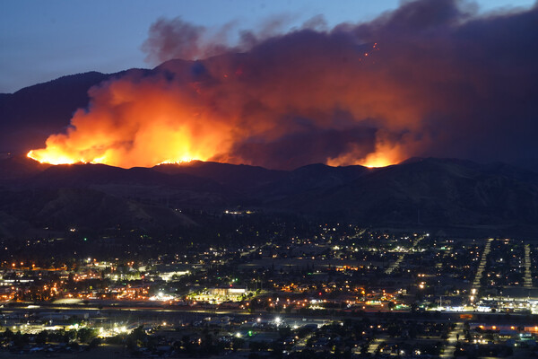 A wildfire rages in the mountains above a city in California.