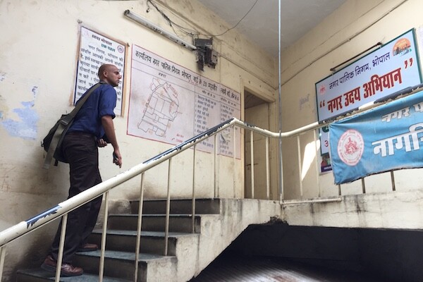 Man walks up stairs. Posters in Hindi hang on the walls. 