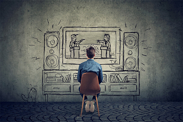 person sits in chair facing wall with drawing of two people debating on a television