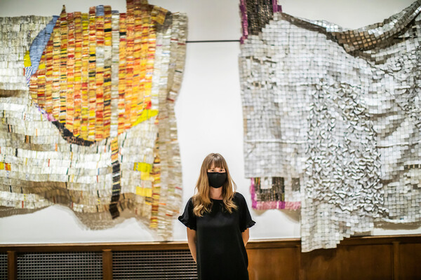 Curator standing in front of two hanging artworks