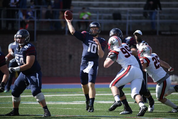 Quarterback Alek Torgersen throws the ball down the field during a game, while being rushed by two defensive players.