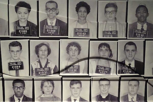 Historical mugshots of 15 people wearing signs around their necks that say, "Police Dept. Jackson, Miss., 7.2.61" along with prison identification numbers