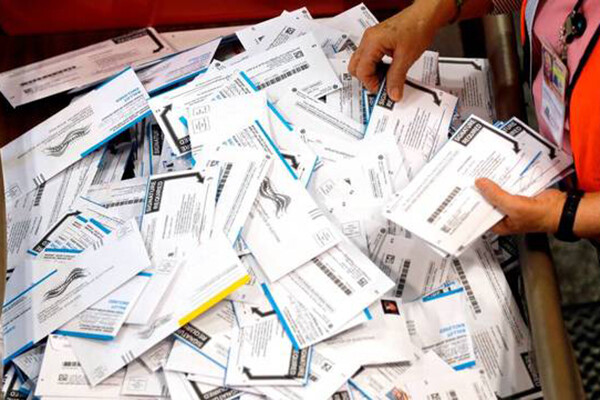 A mail worker sorts through a large pile of mail-in ballots.