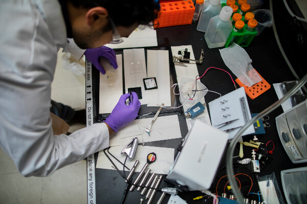 a person bent over with a pair of tweezers while working in a laboratory