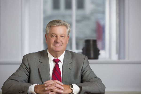 Steve Fluharty seated at a table with hands folded.