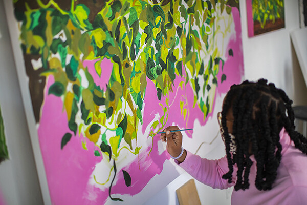 Patricia Renee Thomas paints on a large canvas in her studio.