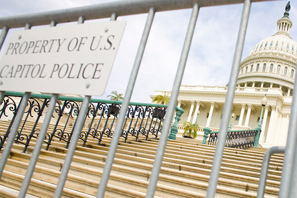 Police fence at foot of stairs to U.S. Capitol with a sign that reads PROPERTY OF U.S. POLICE.