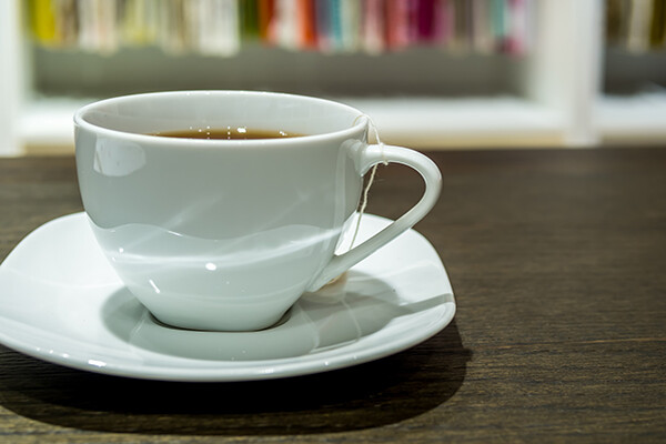 Ceramic tea cup on a saucer on a counter at work.