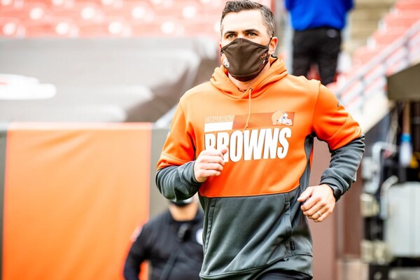 Wearing a Cleveland Browns hoodie and a facemask, Kevin Stefanski runs onto the field.
