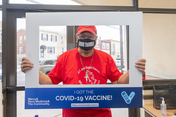 Masked person holds up photo border that reads "I got the COVID-19 vaccine!"