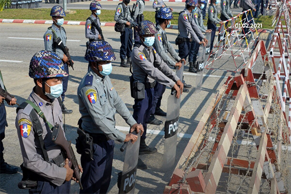 Members of Myanmar police stand by a cordoned off blockade area on the street.
