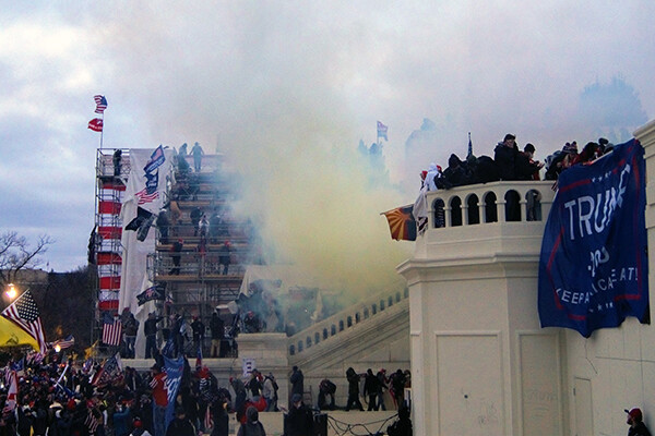 Angry mob on the steps of the U.S. Capitol with tear gas in the air.