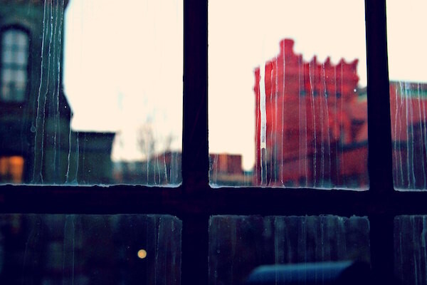 Rain streaks on a gridded window with an image of a red building behind