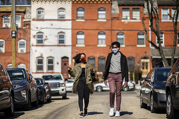 Mckayla Warwick and Kwaku Owusu wear face masks while walking down a street in West Philadelphia.