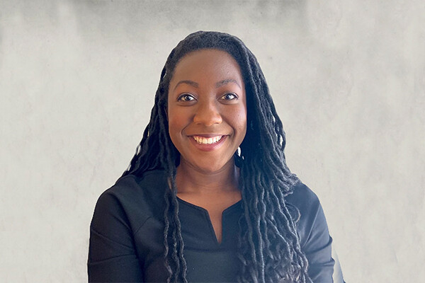 Close up head shot of a smiling young person wearing a black V-neck shirt. 