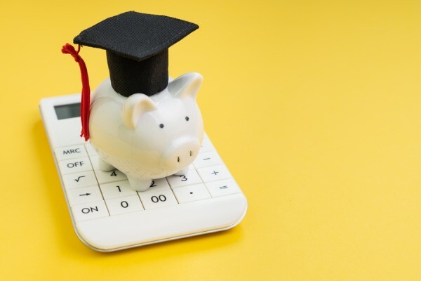 Piggy bank with a graduation cap on top of a pocket calculator.