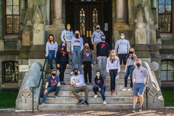 14 students standing on the steps of College Hall 
