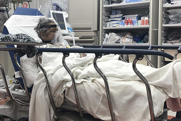 African American COVID patient wearing a respirator in a hospital bed.