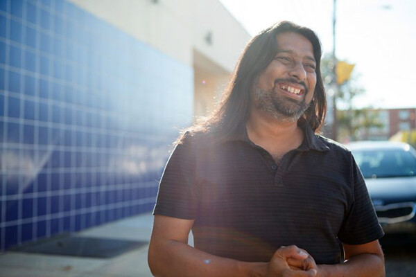 Torju Ghose smiling on a sidewalk in the sunlight.
