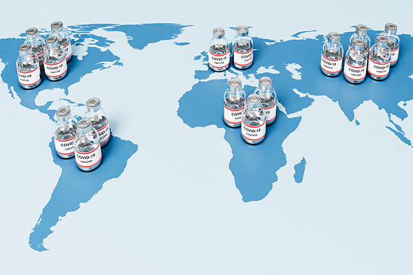 Map of the world with vials of COVID vaccine on top of the map in different countries.