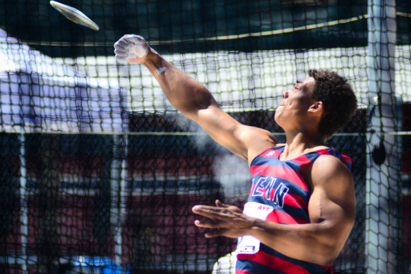 Wearing a red and blue Penn tank top, Sam Mattis throws the discus during his Penn undergraduate days.