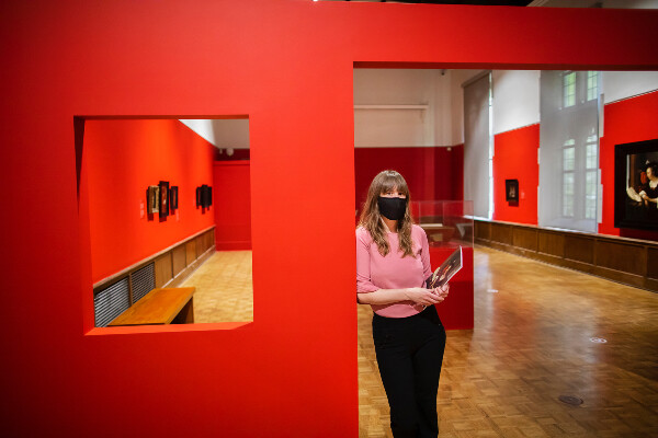 woman standing in doorway of art exhibition with paintings on the walls