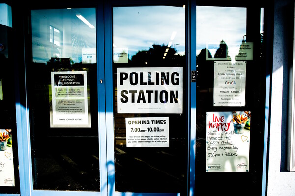 Glass doors read "polling station" with opening times listed