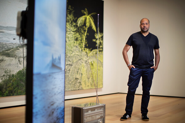 Artist standing in museum gallery with his artwork installation 