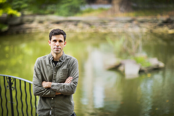 person with arms crossed in front of pond