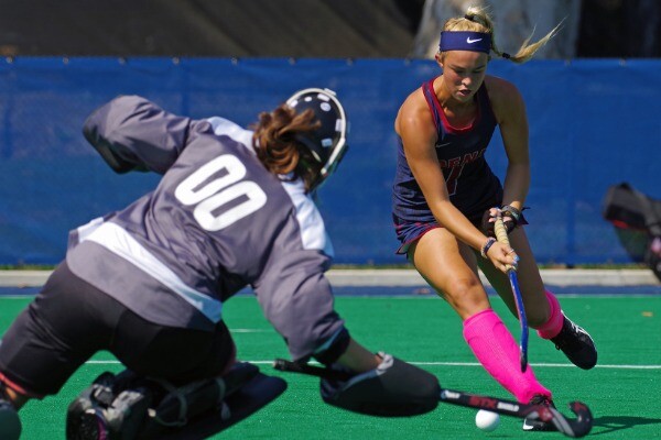 Julia Russo, wearing her blue Penn jersey, with makes move with her stick and ball, in front of the opposing goalie.