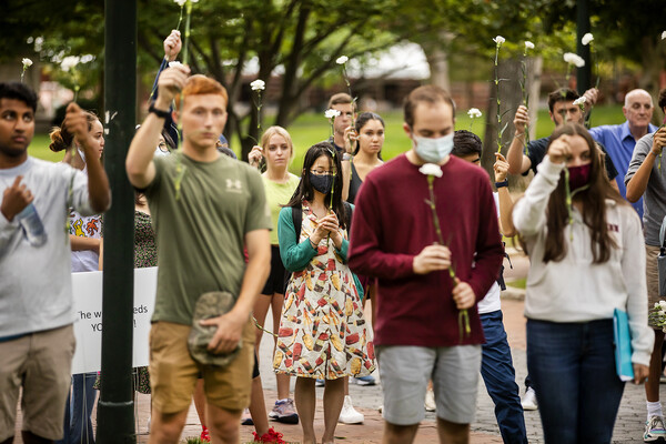 People hold white flowers up during moment of silence