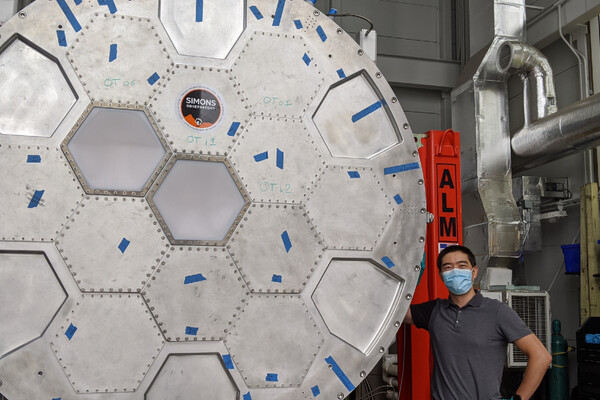 Ningfeng posing next to the large metal LATR inside of a research lab