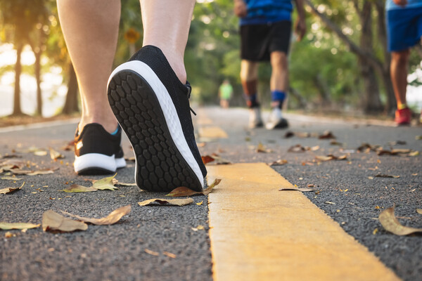 Three people as seen from the ground wearing running shoes on a paved running trail.