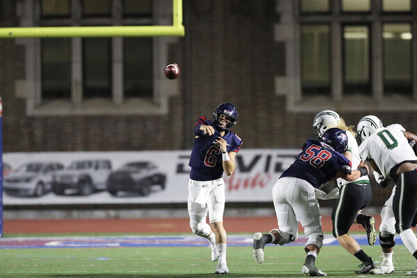 At Franklin Field, quarterback John Quinnelly throws the ball down field, while being rushed by a defender.