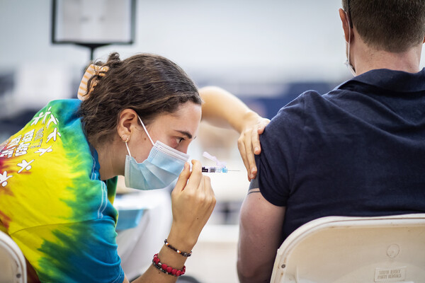health care worker injects vaccine into patient's arm