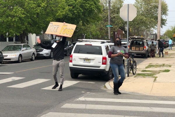 Person holds up sign that says "Free Food" at a distribution event