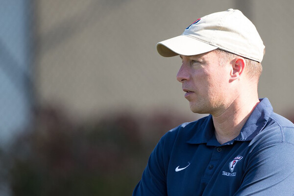 Wearing a beige Penn hat and a blue Penn track and field shirt, Steve Dolan looks to the left.
