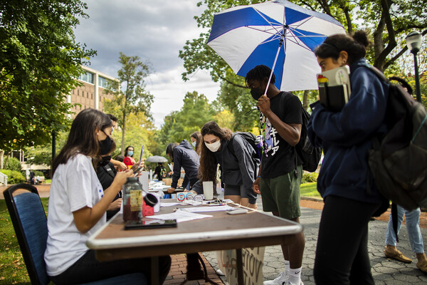 Students bend over to fill out paperwork on a table