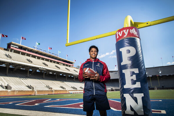 Standing near the goalpost in the endzone at Franklin Field, Laquan McKever holds a football and wears a Penn jacket.
