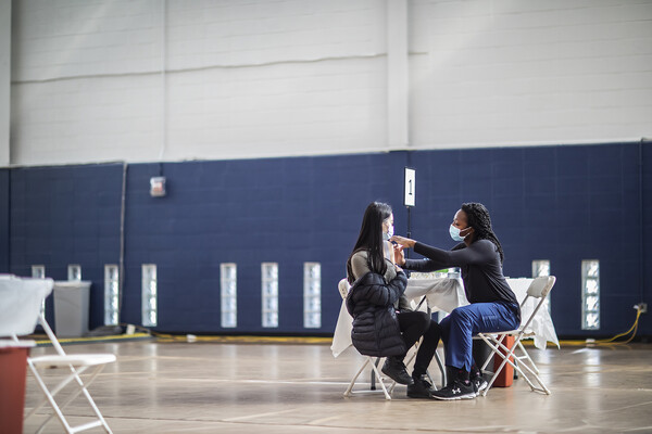 a person in a gymnasium getting a vaccine while wearing a mask