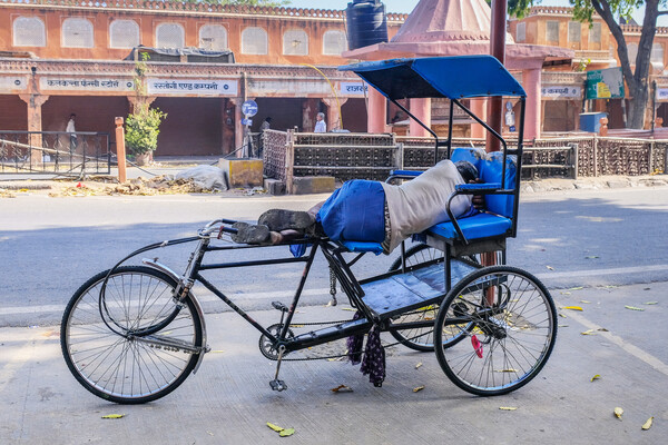 Person asleep on a bicycle rickshaw in India.
