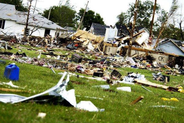 Aftermath of severe storm on a neighborhood with damaged houses and strewn debris.