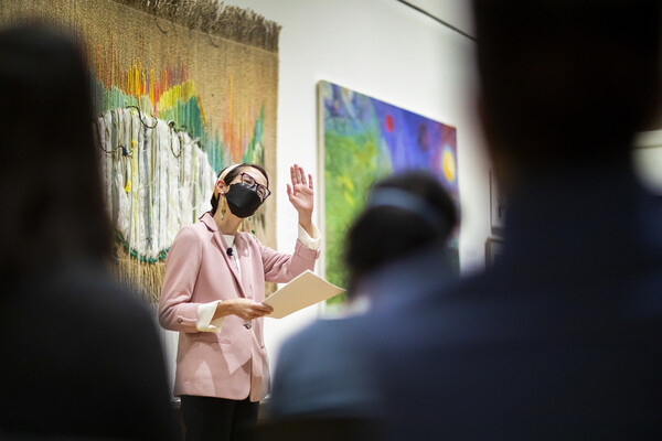 curator standing in front of artwork speaking with hand raised 