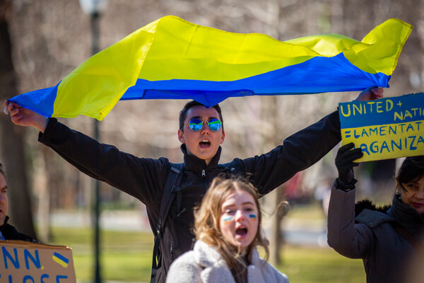 Person holding a Ukrainian flag at a solidarity with Ukraine rally on Penn’s campus.