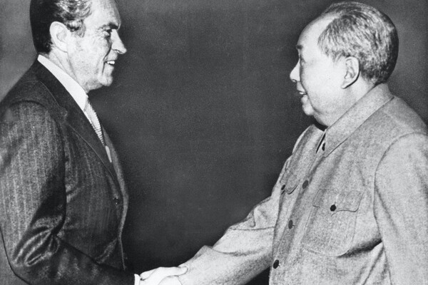 President Richard Nixon smiles and shakes hands with a smiling Chairman Mao